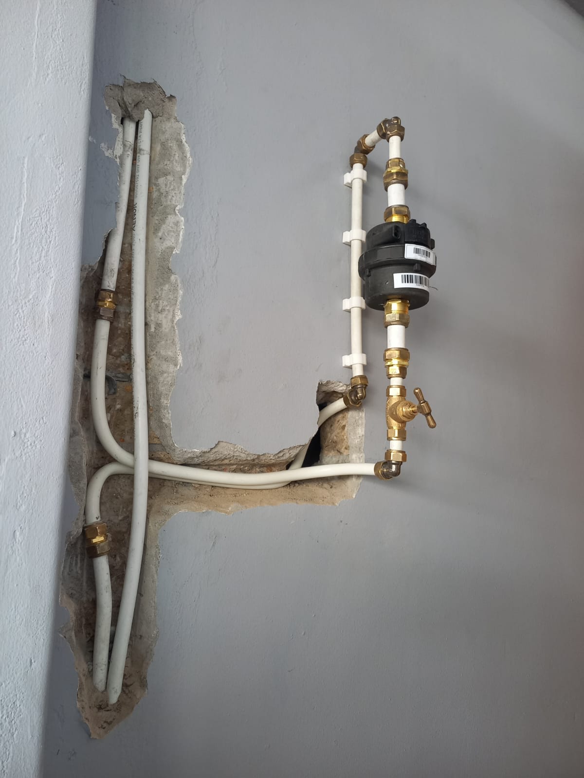 Externally mounted water meter with brass compression fittings and isolation valve on a Cape Town property wall